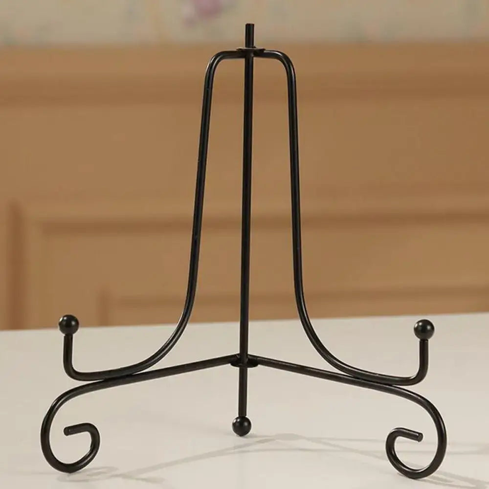 Single black iron plate rack easel with scroll design and ball tips. Sturdy and stylish for home or office decorative displays.