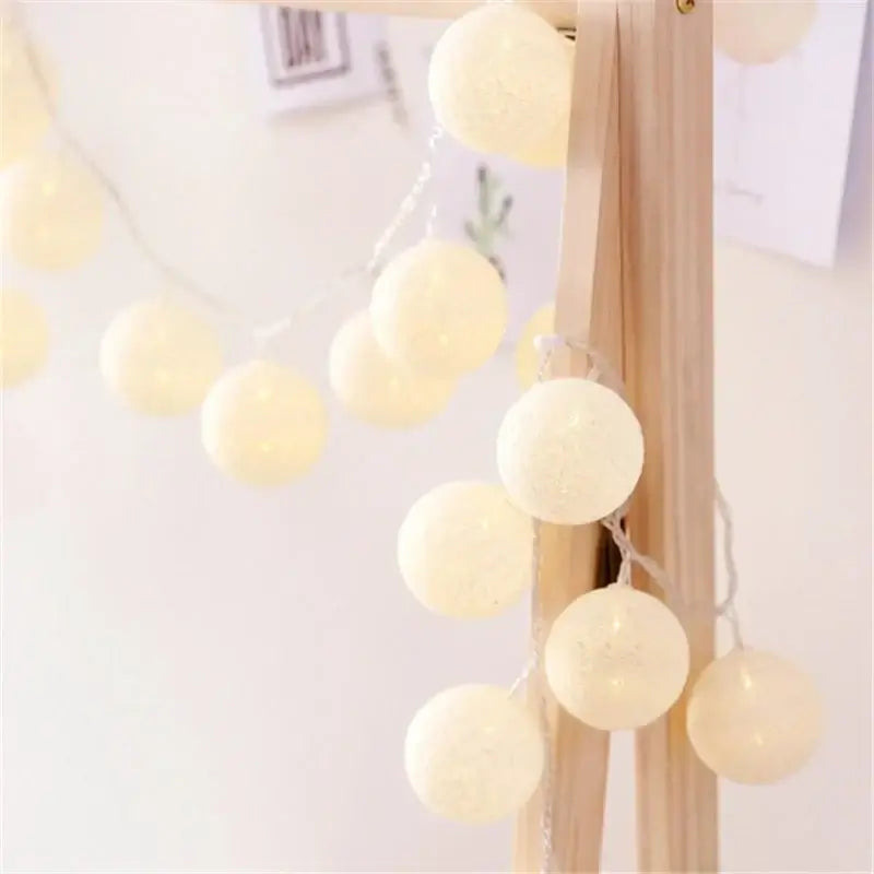 Cream white LED String Lights Cotton Balls hanging on a wooden frame, ideal for minimal and elegant home lighting.