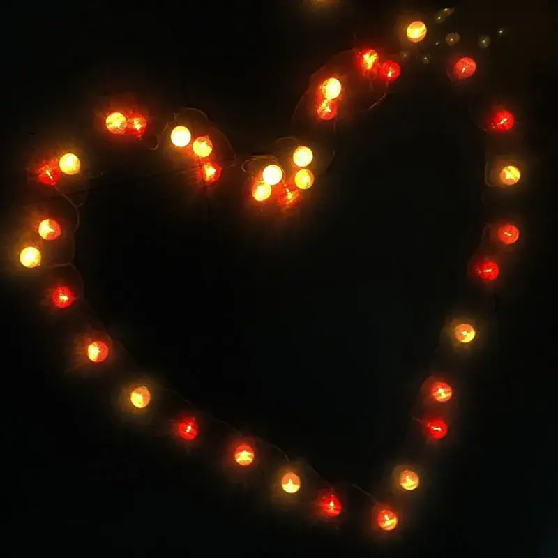 Heart-shaped arrangement of red and yellow LED String Lights Cotton Balls, great for romantic or themed decorations.