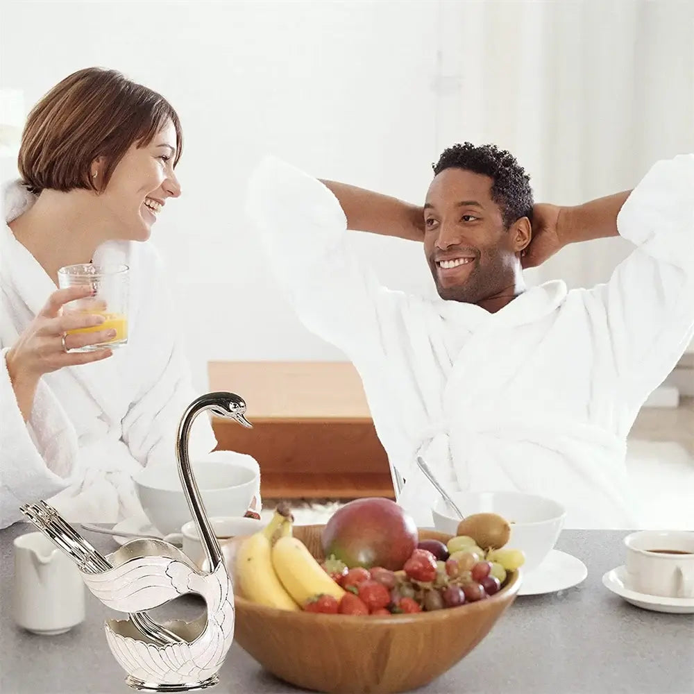 Silver Swan Spoon Holder Set on a breakfast table with fruit bowl, adding charm to a cozy morning dining experience.