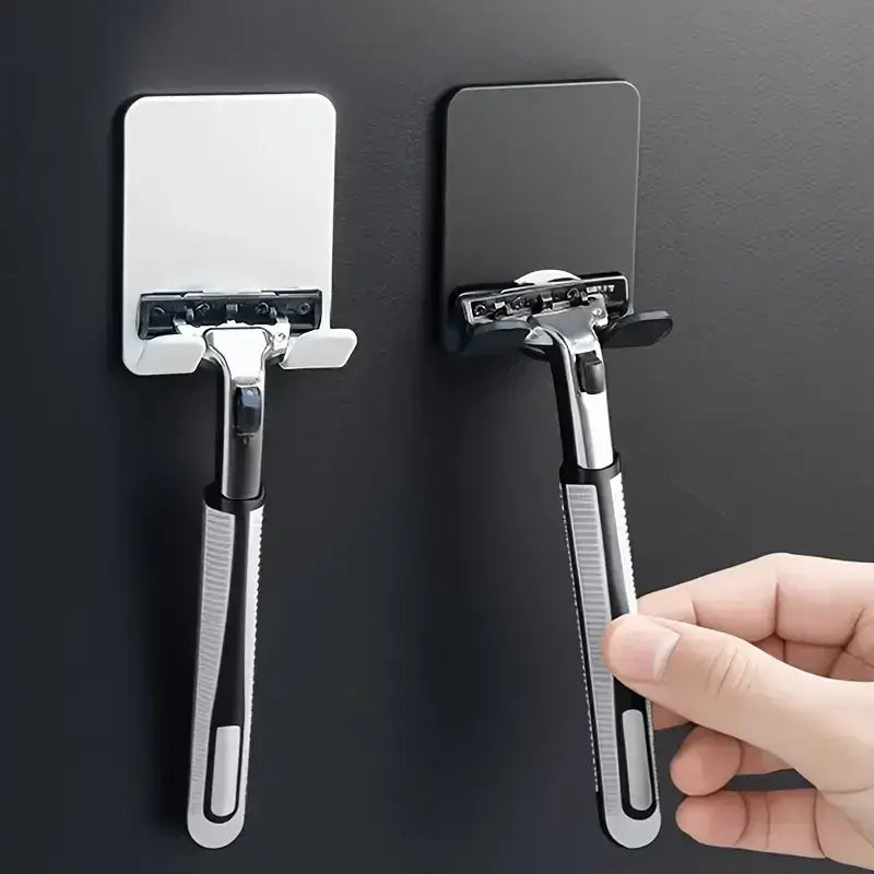 Wall mounted adhesive razor holder in black and white, rustproof and waterproof, ideal for organizing razors in modern bathrooms.
