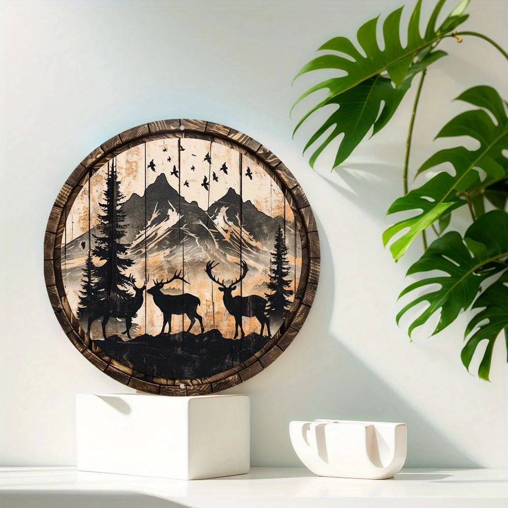 Round metal deer sign mounted on a white wall with green plant decor. Showcases elk and buck in a forest with mountain background.
