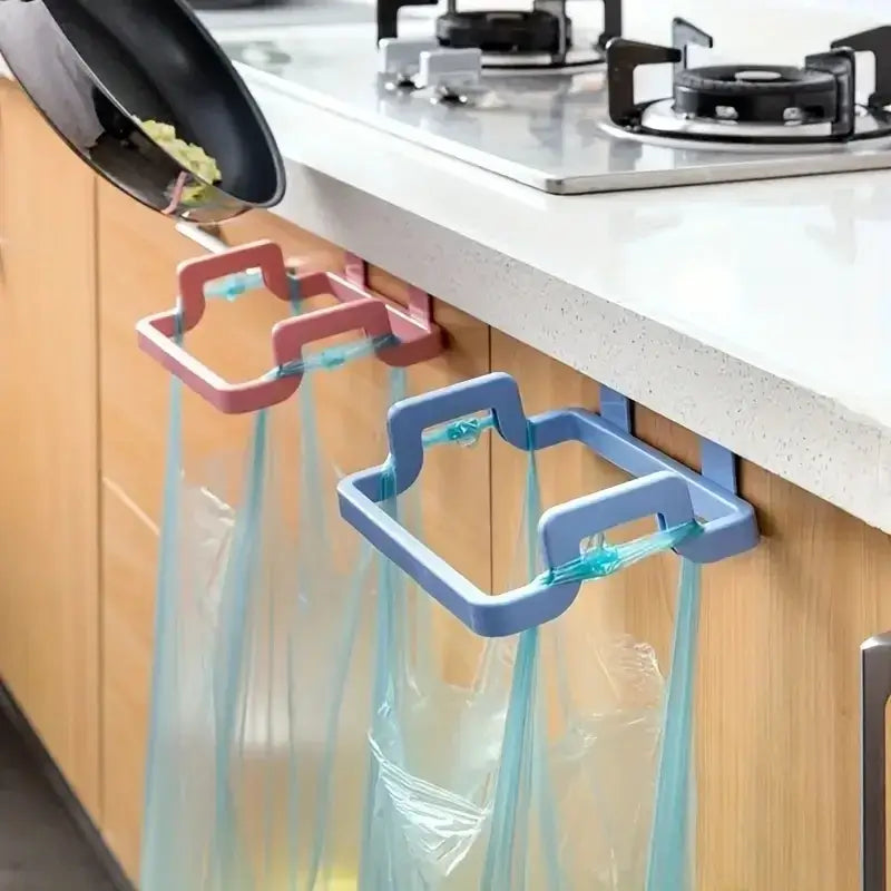 Pink and blue trash bag hooks mounted on kitchen cabinet doors. Ideal for clutter-free waste management during cooking.