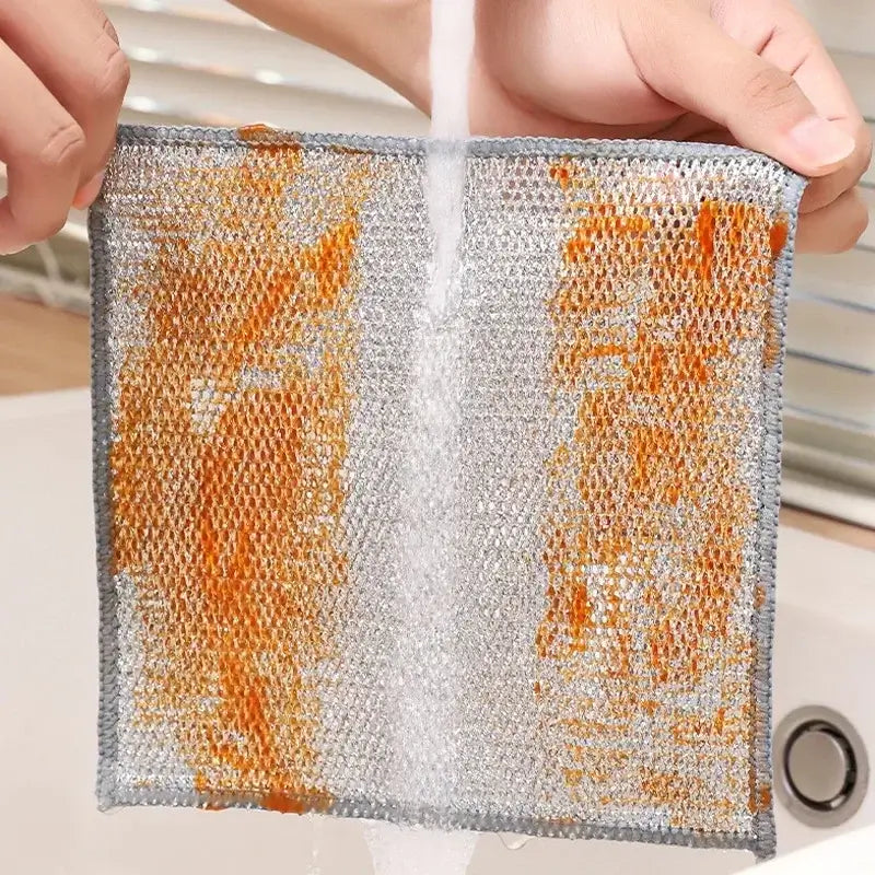 Magic Dishcloth Silver Wire being rinsed clean of heavy grease, showcasing its easy-to-clean and durable mesh design.