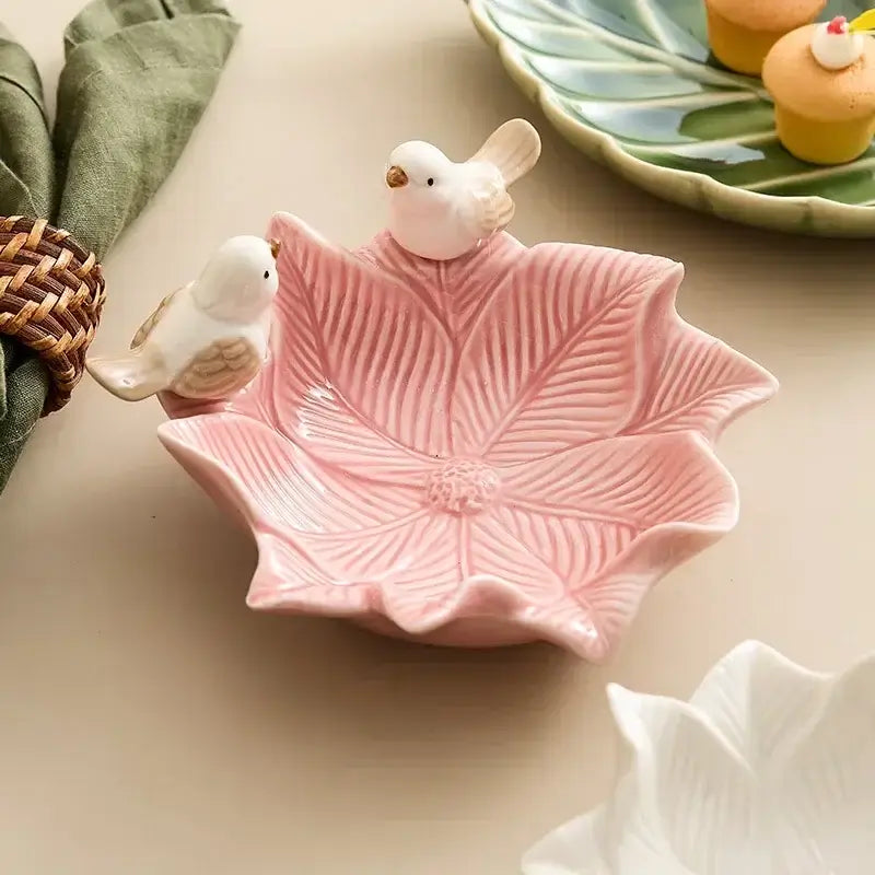 Pink flower-shaped ceramic jewelry tray featuring two perched bird figurines, ideal for organizing rings and earrings on vanities.