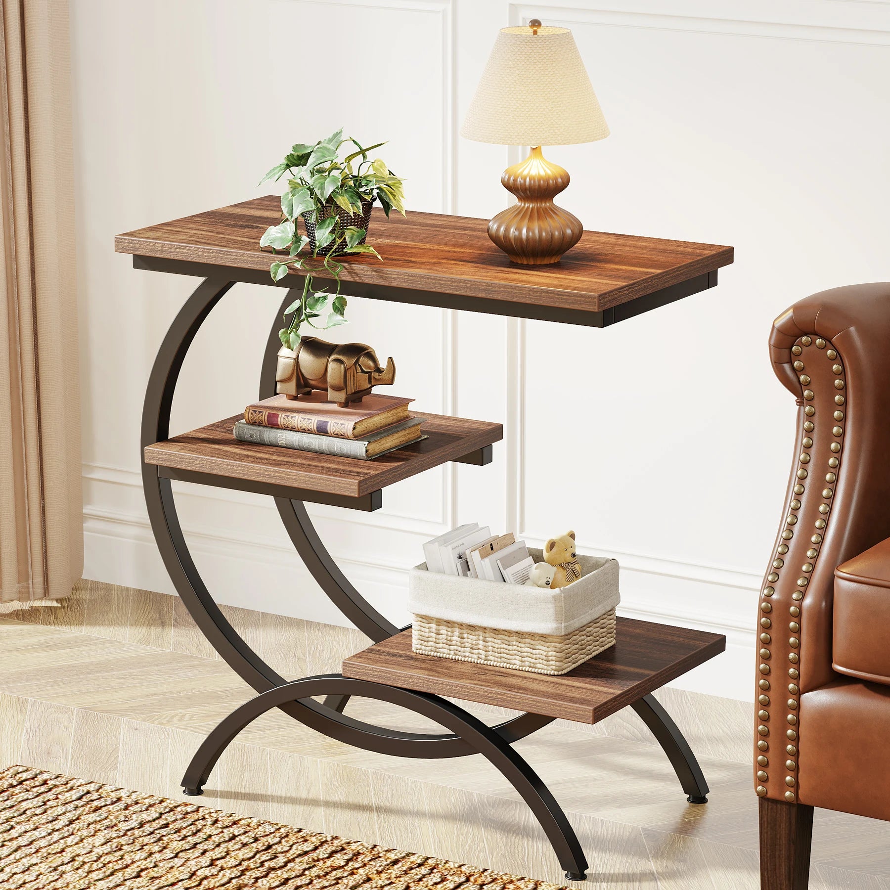 3-tier couch table with rustic wood shelves and black C-shape frame, styled with lamp and decor beside a brown leather chair.