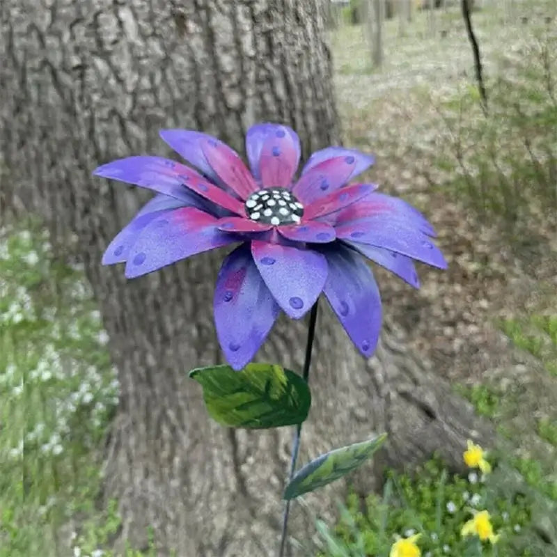 Purple Metal Flower Garden Stake with black and white center, placed in a natural outdoor setting for decorative yard art.