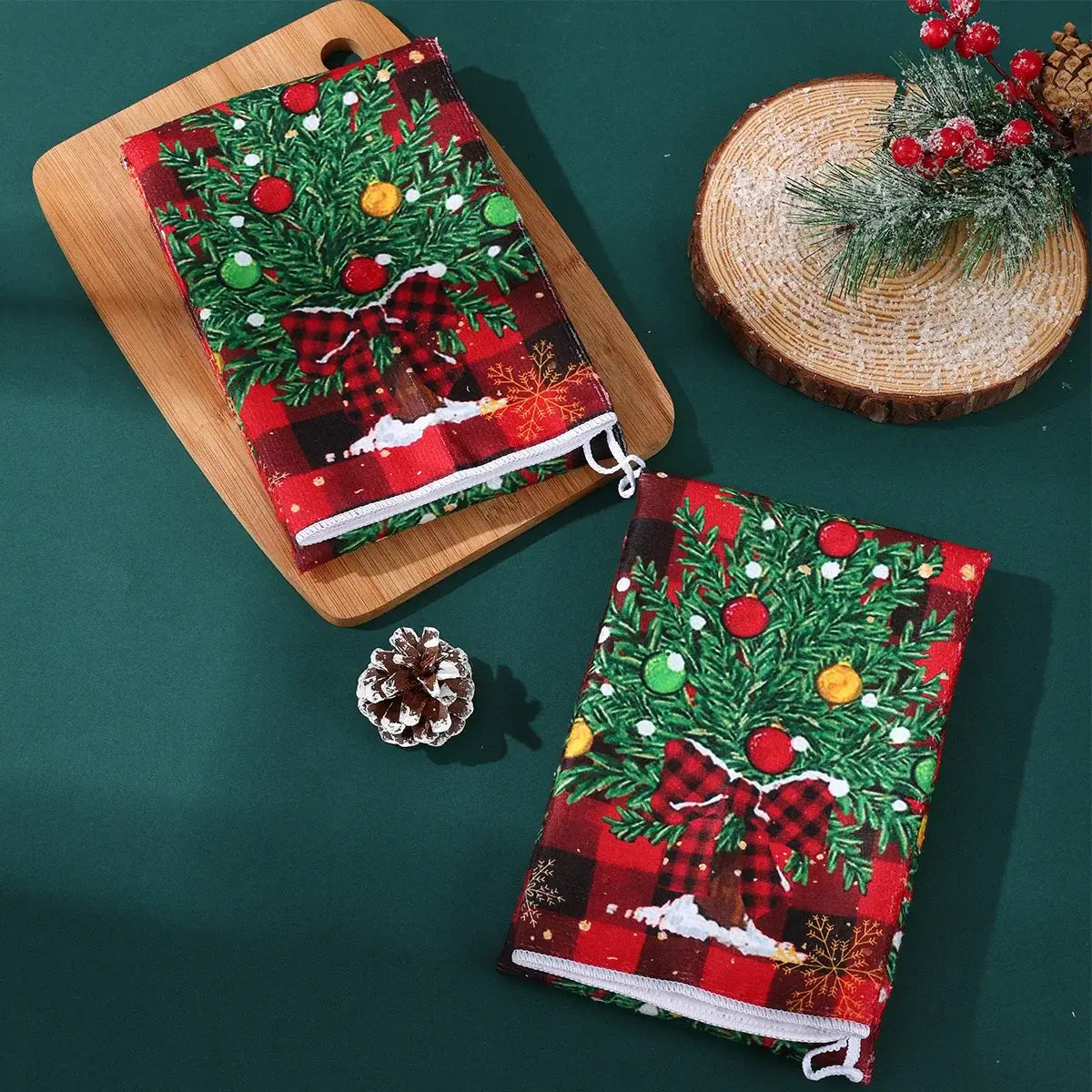 Folded Christmas kitchen towels with decorated tree and plaid background. Festive cotton towels for seasonal kitchen use.
