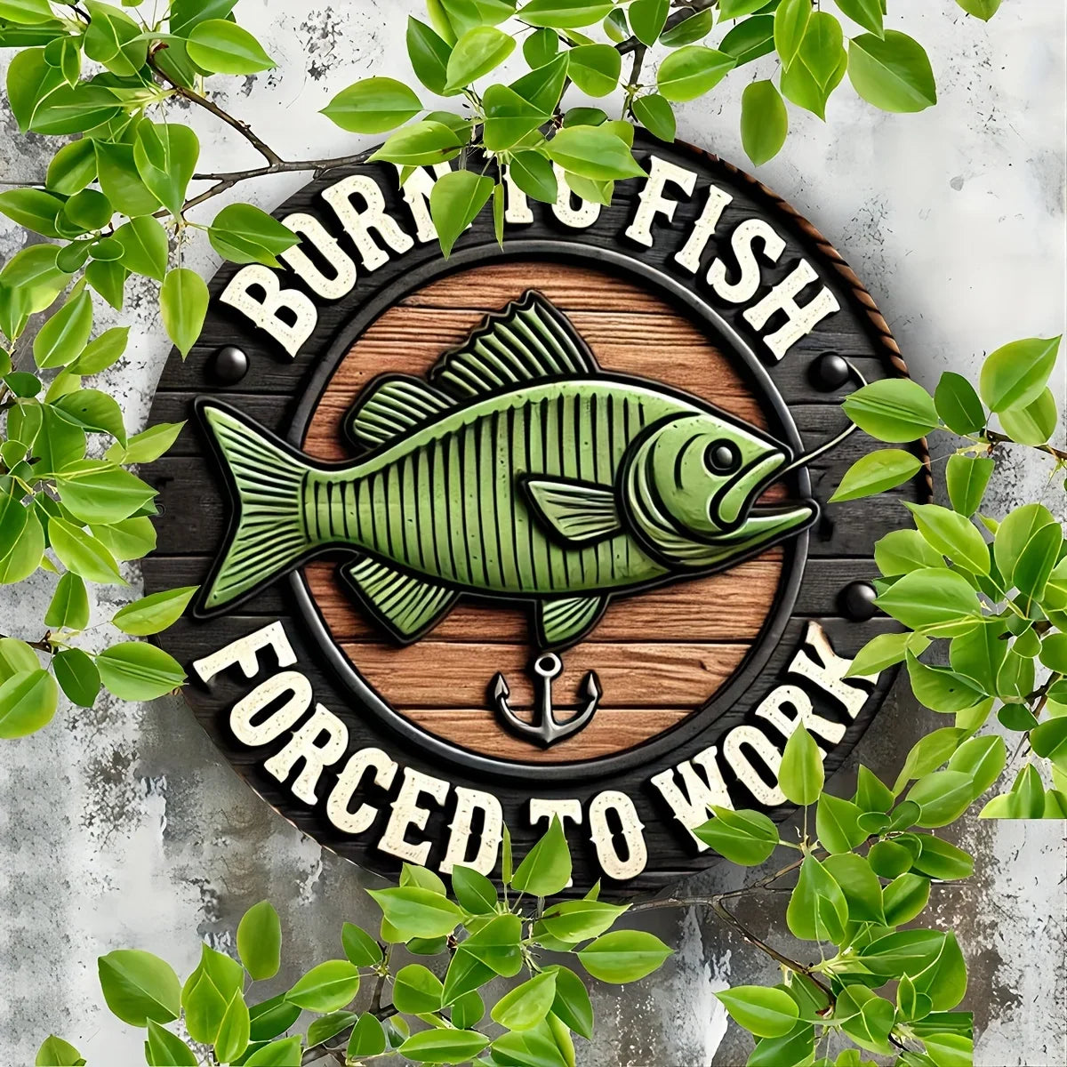 Durable Fishing Enthusiast metal sign with anchor and green fish design, shown on a weathered wall with leafy greenery.