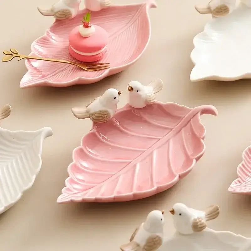 Assorted pink and white ceramic leaf jewelry trays with bird figurines, designed for elegant accessory organization.