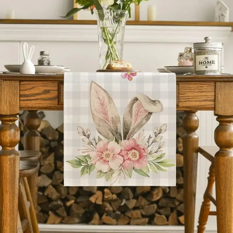 Linen Easter Bunny Table Runner with floral bunny ear design on a checkered background. Adds spring charm to dining tables and Easter decor.