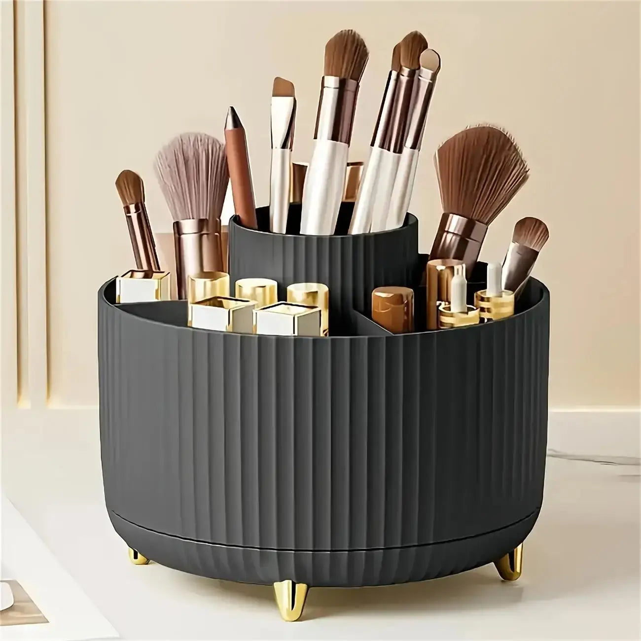 Black 360 rotating storage box with 5 compartments neatly organizing makeup brushes and lipsticks on a beige surface.