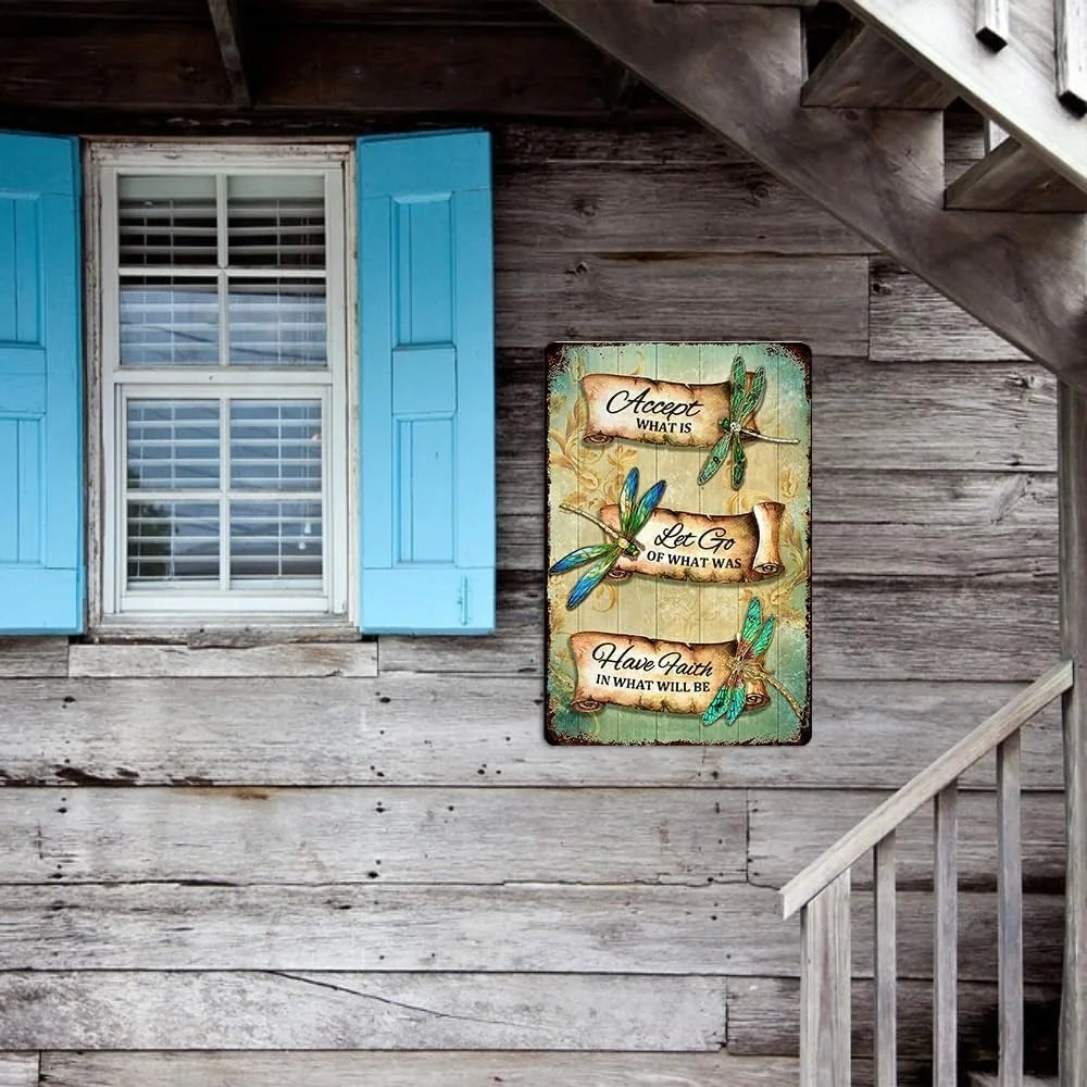Retro Dragonfly Tin Sign on rustic wooden wall near blue window shutters. Enhances farmhouse or cottage-style outdoor decor.