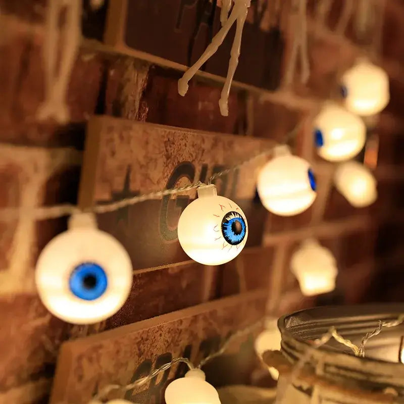 Blue eyeball Halloween LED string lights on a brick wall. Adds eerie charm to seasonal home decorations.