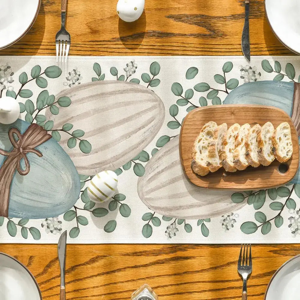 Top view of Easter table runner with eucalyptus and egg illustrations, paired with bread and plates. Enhances festive table presentation.