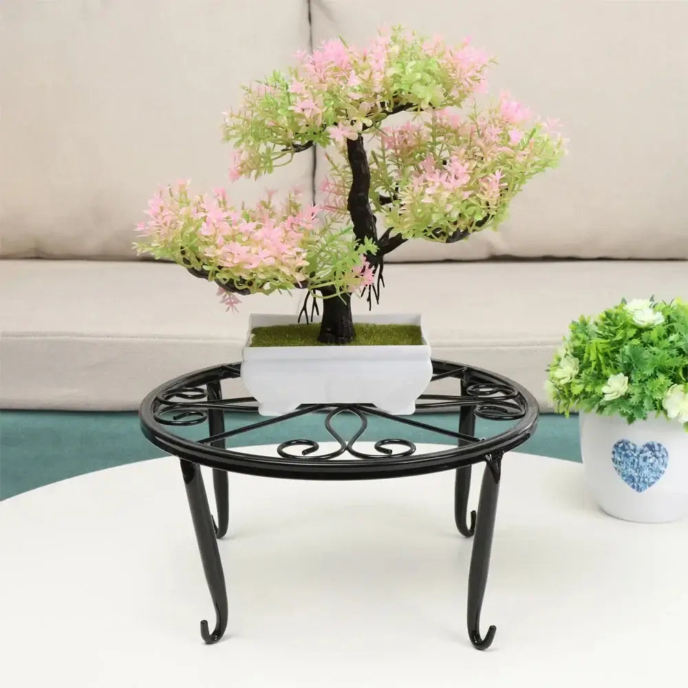 Black metal plant stand with scrollwork design displaying a bonsai tree, suitable for indoor garden or patio decoration.