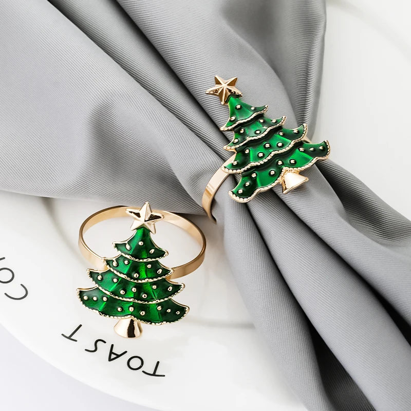 Two Christmas tree napkin rings on gray napkin, showcasing detailed green and gold holiday design for stylish seasonal table decor.