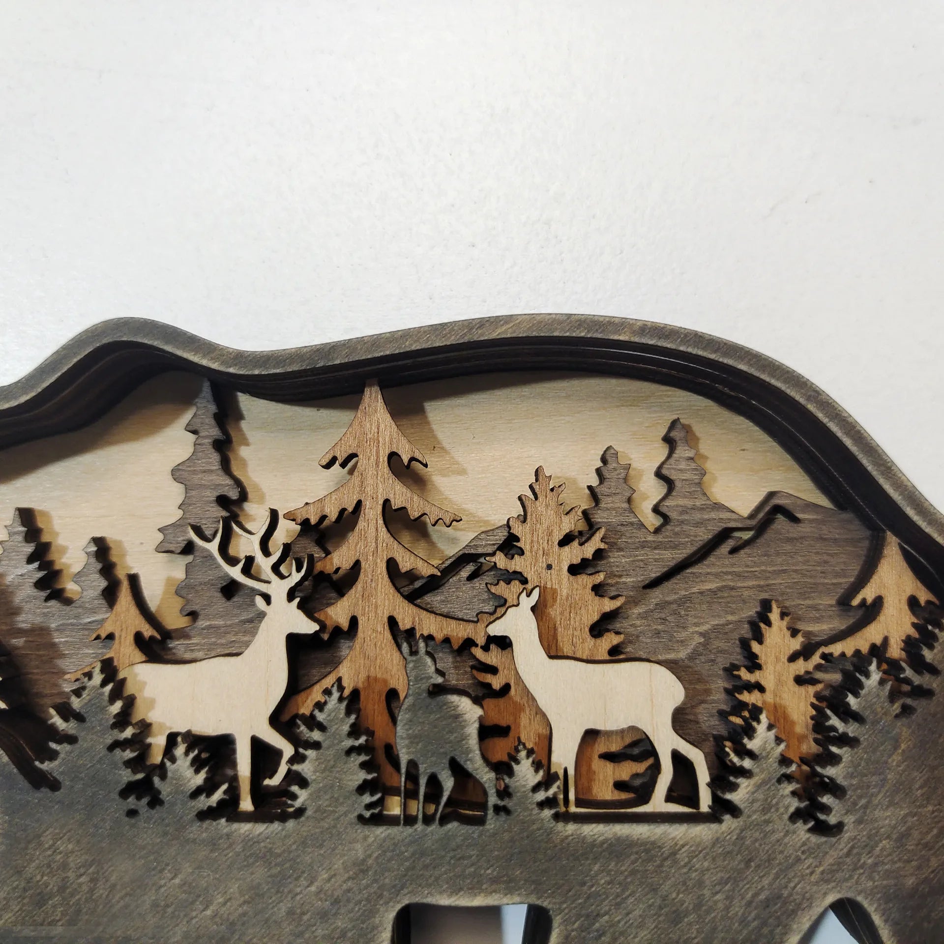 Close-up of wooden bear figurine showing detailed forest and deer carvings, handcrafted for decorative rustic charm.