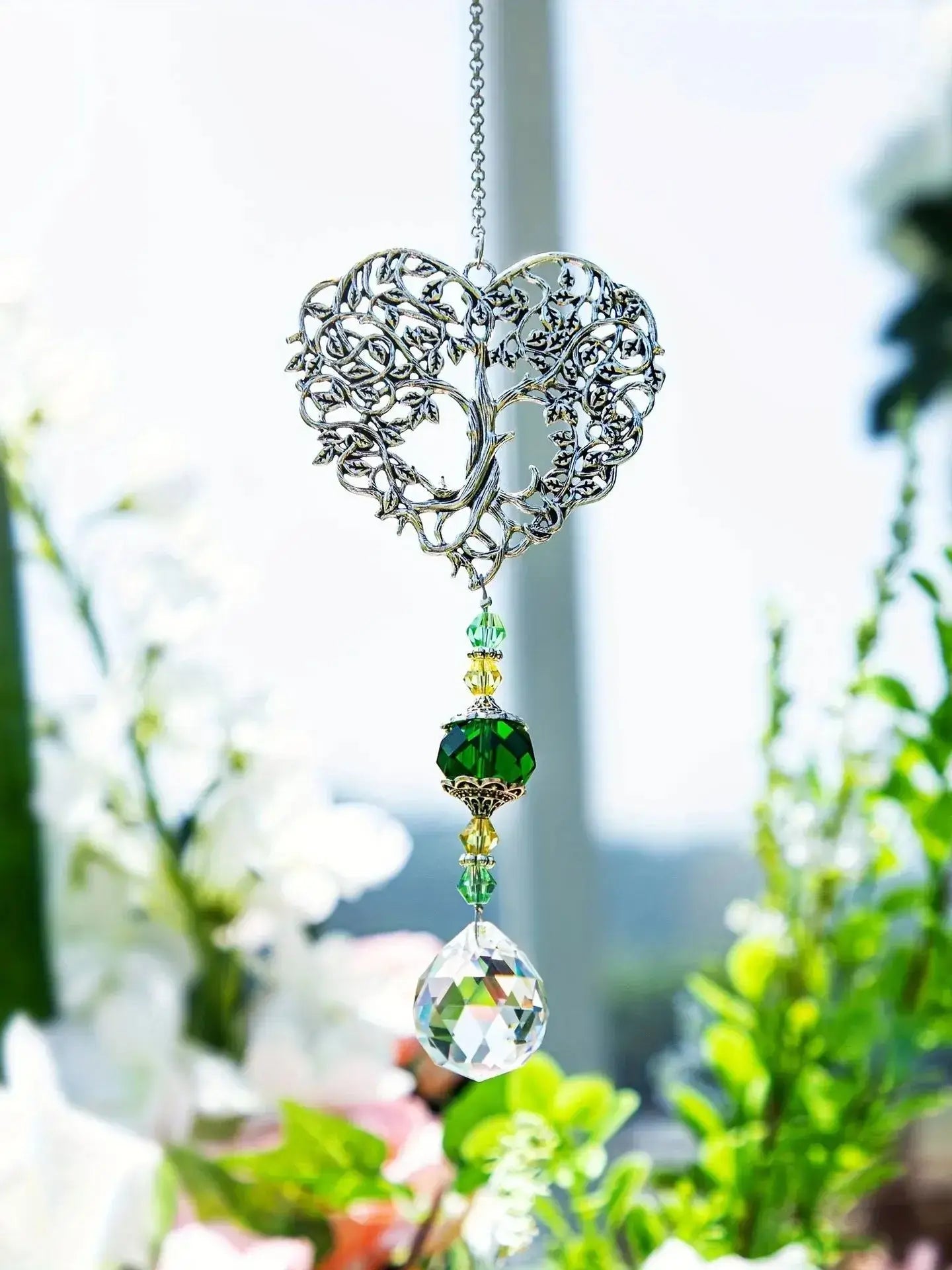 Tree of Life Suncatcher - Crystal Pendant hanging in bright floral surroundings, enhancing window spaces with vibrant reflections.