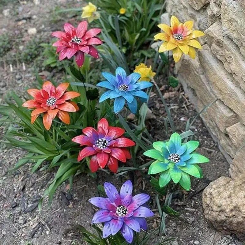 Colorful Metal Flowers Garden Stakes arranged in soil near rocks, ideal for outdoor yard art and metal garden décor.