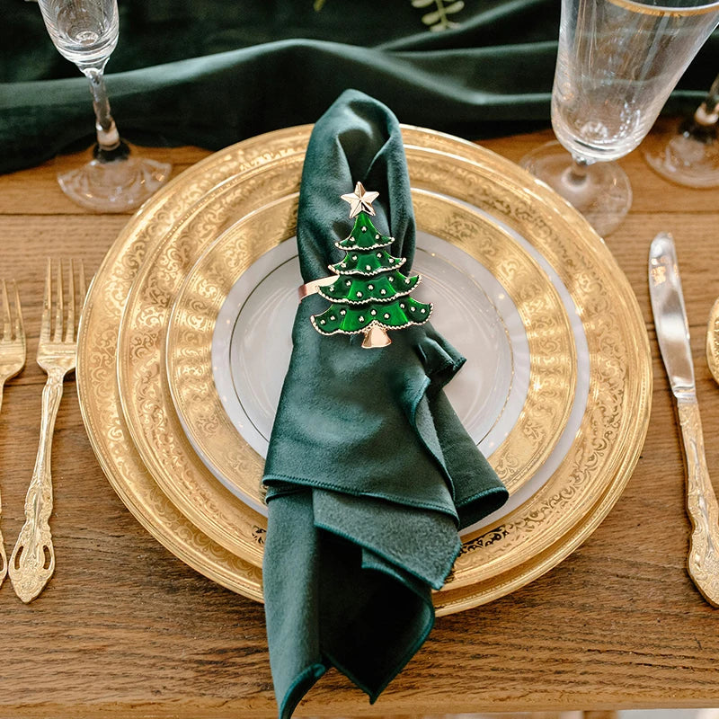 Christmas tree napkin ring on dark green napkin atop elegant gold-rimmed plate, ideal for holiday table decoration and festive dining ambiance.