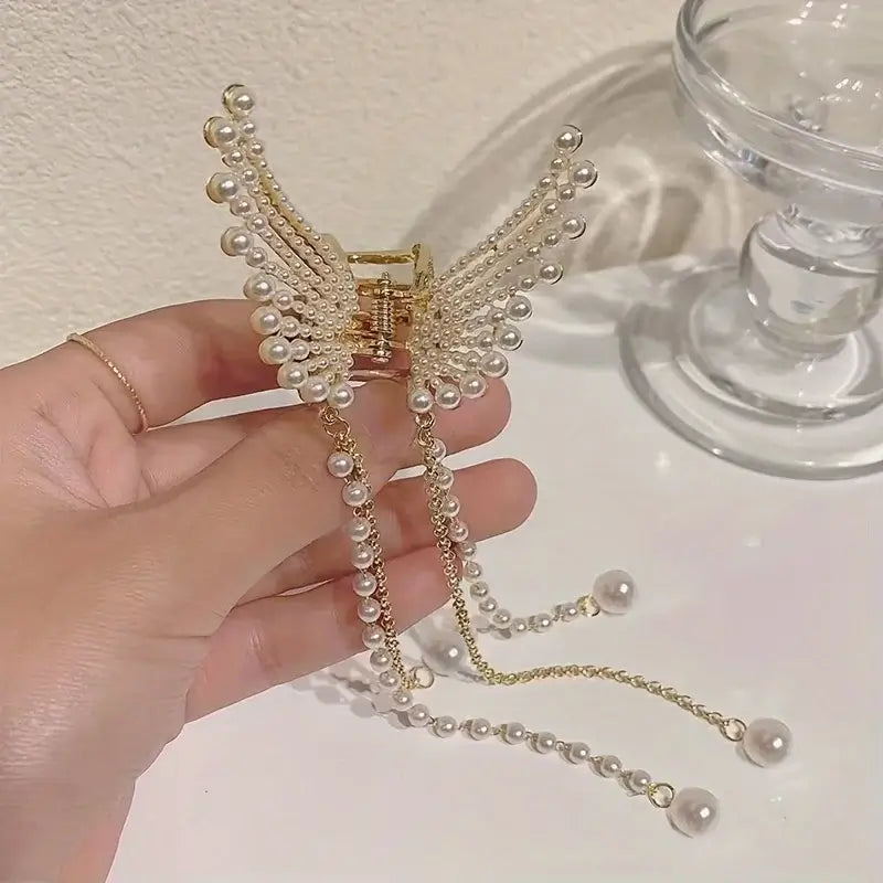 Women Butterfly Tassel Hair Clip displayed on white surface. Gold clip with pearl accents and flowing tassels for a delicate, feminine touch.
