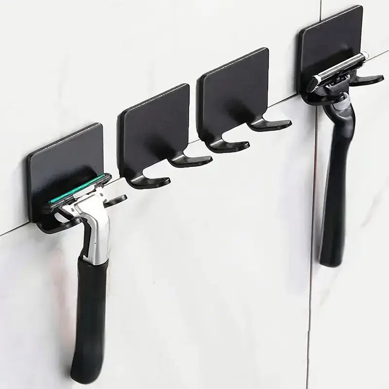 Set of black wall mounted adhesive razor holders on a tiled bathroom wall, perfect for holding razors securely without drilling.