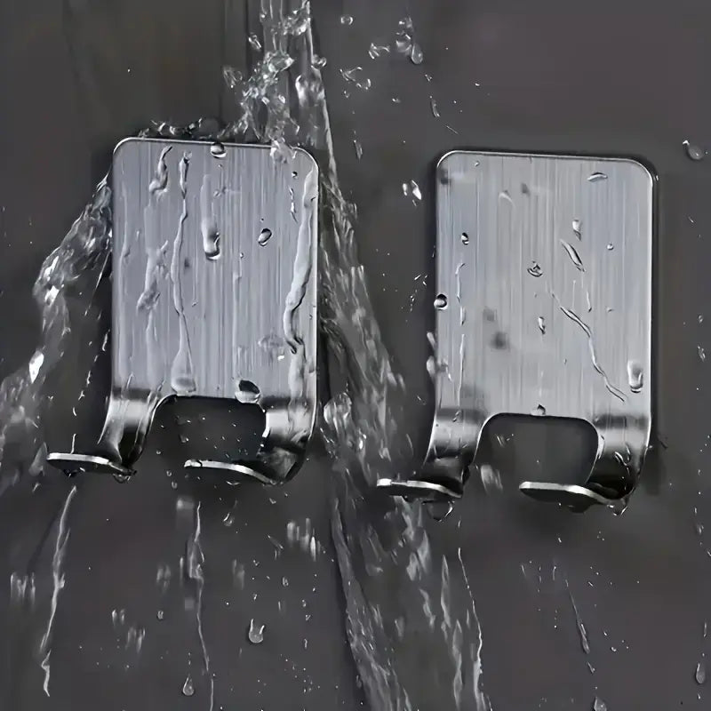 Two stainless steel adhesive razor holders under running water, highlighting waterproof and rustproof features for shower use.