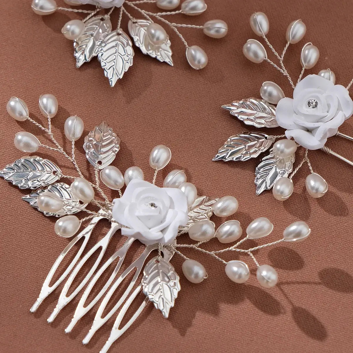 Close-up of white handmade flower hair comb set with imitation pearls and silver leaves, ideal for weddings or special events.