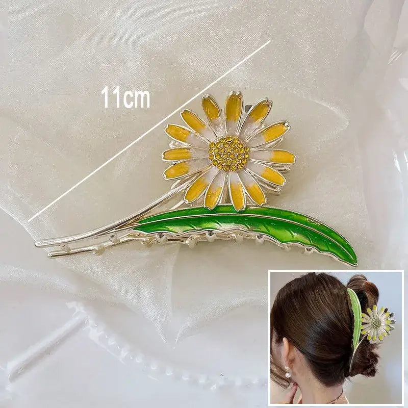 Yellow daisy ponytail hair clip with green leaf, 11cm long, offering a secure and cheerful floral touch to hairstyles.