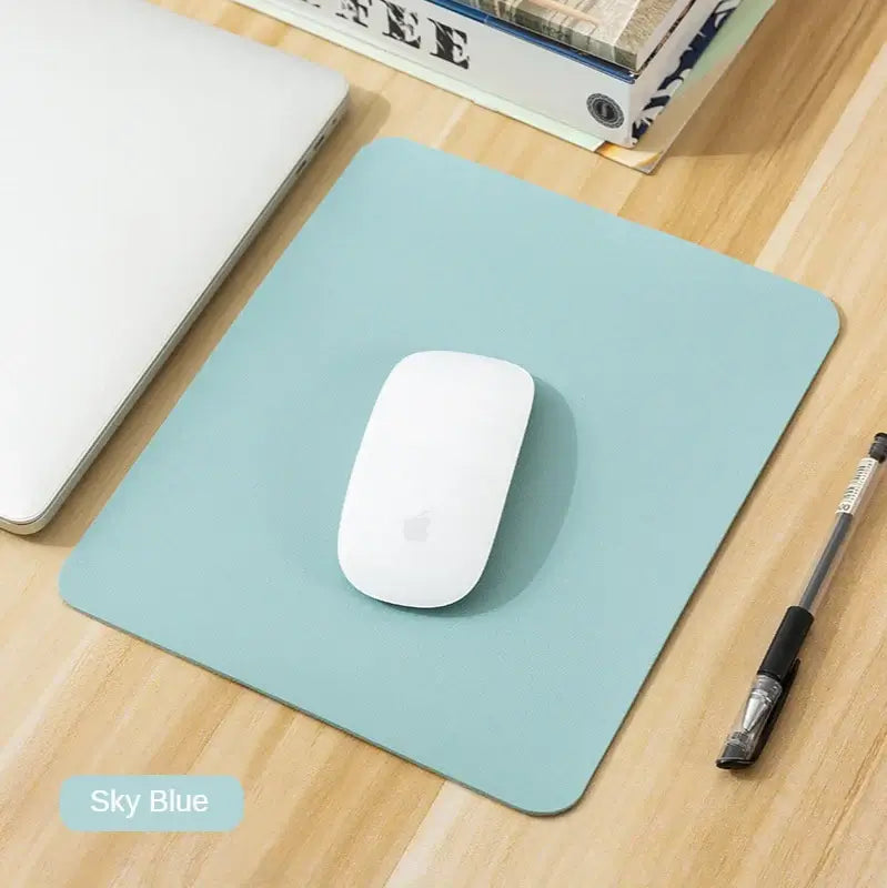 Sky blue Small PU Leather Gaming Mouse Pad with non-slip surface, shown with a white mouse on a wooden desk.