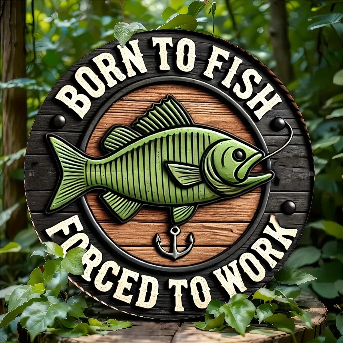 Fishing Enthusiast metal sign with green fish and 'Born to Fish, Forced to Work' text, displayed outdoors among green foliage.