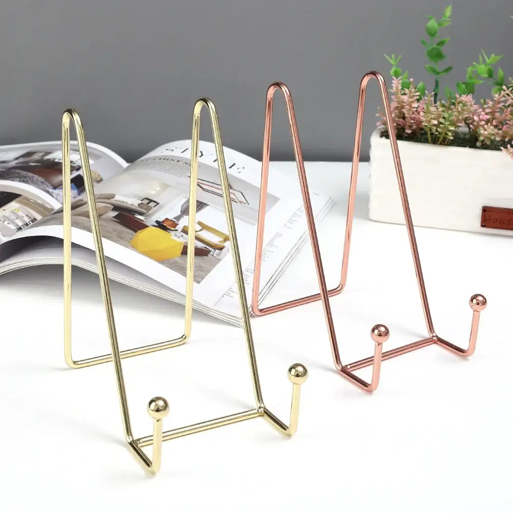 Tall gold and rose gold art display frame stands beside a magazine. Sleek design for displaying frames or artwork.