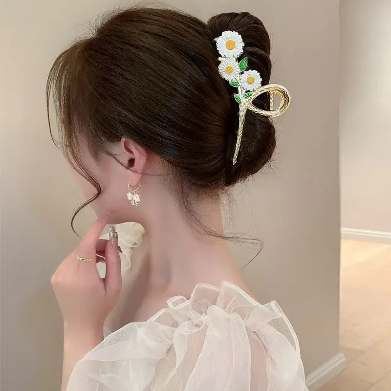 White daisy ponytail hair clip with gold accents, designed for a secure and stylish hold on all hair types.