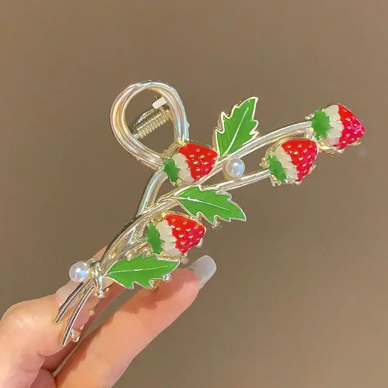 Close-up of strawberry ponytail hair clip featuring red berries, green leaves, and pearl accents for a secure and cute look.